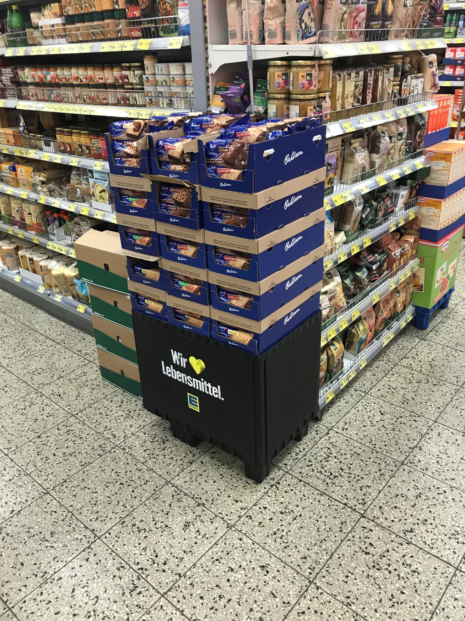 A smart merchandise display on skids in a supermarket aisle holding biscuits